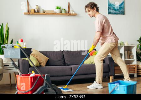 A handsome man in cozy homewear meticulously cleans a living room with a mop. Stock Photo