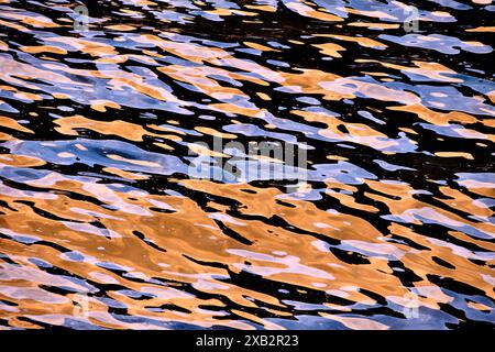 An intricate pattern of golden and blue ripples reflecting on the water's surface, creating a mesmerizing abstract visual, Spain Stock Photo