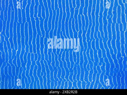 This image features a vibrant blue textured surface with a distinctive crack pattern, creating a sense of movement and texture that is both visual and Stock Photo