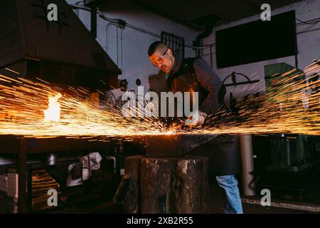 A skilled male blacksmith forges with intense heat, sending sparks flying in all directions. Stock Photo