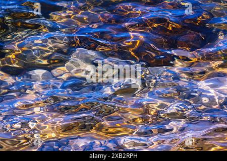 This image captures the mesmerizing patterns and colors reflected on the sea's surface, presenting an abstract tapestry woven by sunlight interacting Stock Photo