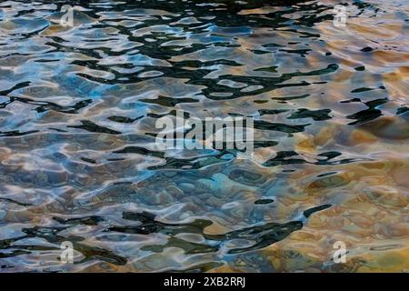 This image captures the intricate patterns and vibrant shades reflected on the surface of the sea, showcasing a dynamic blend of blues, grays, and sub Stock Photo