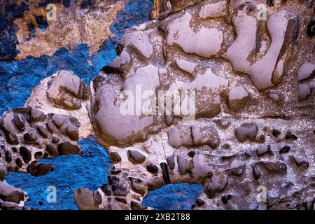 Fine art photo capturing the unique erosion patterns and textures on a rocky surface with a vibrant blue hue. Stock Photo