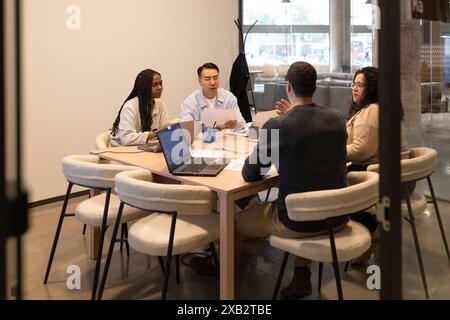 Diverse group of young professionals engaged in a meeting at a modern coworking space Stock Photo