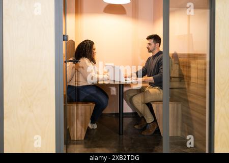 Two friends collaborate on a project in a cozy coworking space, sharing insights and ideas over a laptop Stock Photo