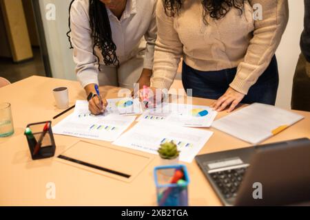A diverse team collaborates on a business project, analyzing charts and graphs in a modern coworking environment Stock Photo