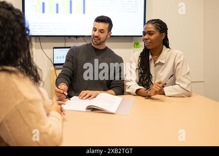 A diverse team collaborating in a modern coworking space with charts displayed Stock Photo