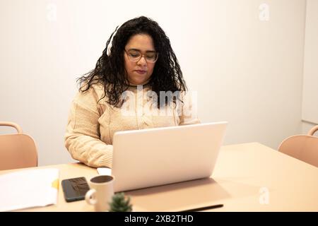 A focused individual works attentively on a laptop in a modern coworking space, highlighting the collaborative environment of a friends team Stock Photo