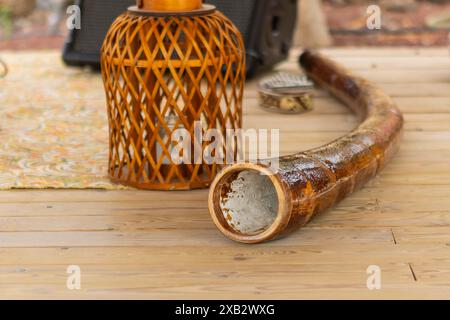 A close-up view of a didgeridoo, used for sound therapy, displayed on a wooden floor with intricate details visible on the instruments. Stock Photo