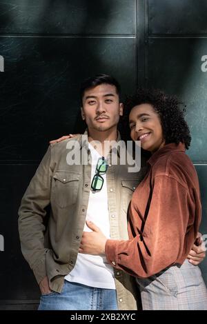 Portrait of a multiethnic couple, consisting of a Chinese man and a Hispanic woman, shares a tender moment while posing together looking at camera in Stock Photo