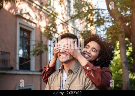 A multiethnic couple composed of a Chinese man and a Hispanic woman share playful, affectionate moments while strolling through the picturesque street Stock Photo