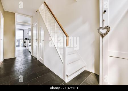 A well-lit hallway featuring a white staircase and dark floor tiles located at Roggebotstraat in Amsterdam The entryway is elegantly decorated, captur Stock Photo