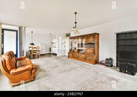 An ample living room featuring a vintage wooden cabinet set and a leather sofa, located on Simone de Beauvoirstraat in the Netherlands Stock Photo
