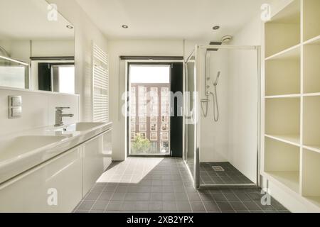 Bright and spacious bathroom featuring a sleek double sink, glass-enclosed shower, and large window with cityscape view. Modern design elements with a Stock Photo