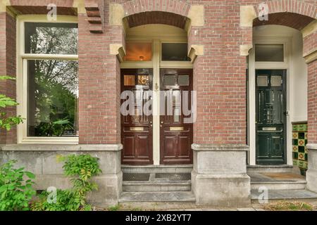 Classic red brick house facade with ornate wooden doors and white windows. Stock Photo