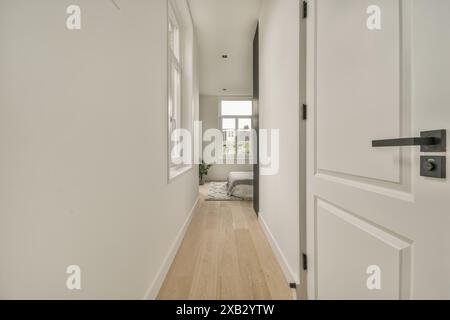 A well-lit hallway in a contemporary home, featuring sleek white walls, wooden flooring, and minimalist decor. Stock Photo