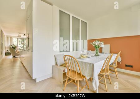 A contemporary dining space with an elegant wooden table set, earth-tone walls, and natural light. Stock Photo