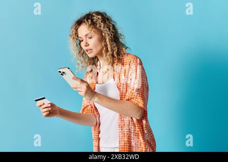 Woman with curly hair holds cell phone and credit card. Stock Photo