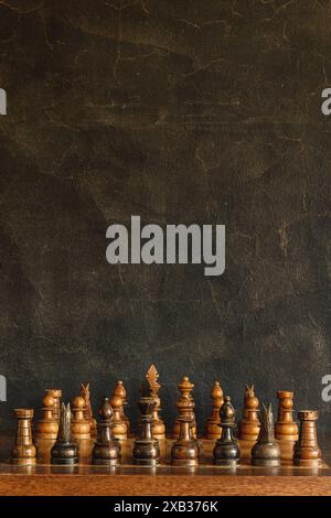 Antique weathered wooden chess game pieces in front of a textured black background Stock Photo