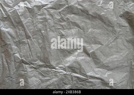 Silver gray plastic film with embossed dots background. Wrinkled gray film texture. Grunge backdrop. Stock Photo