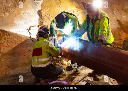 Male workers uses machinery while cutting pipe in construction industry Stock Photo