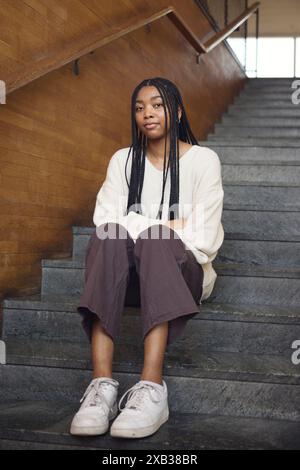 Young woman with braided hair sitting on staircase Stock Photo