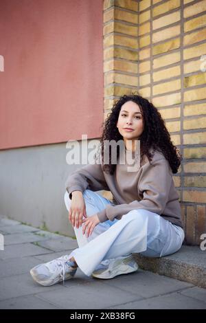 Smiling beautiful woman sitting on footpath Stock Photo