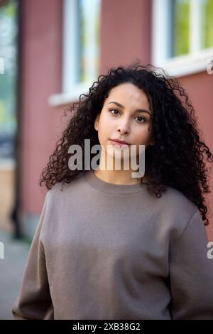 Beautiful curly haired woman against building Stock Photo