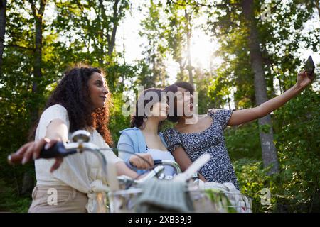 Happy woman taking selfie with friends through mobile phone Stock Photo
