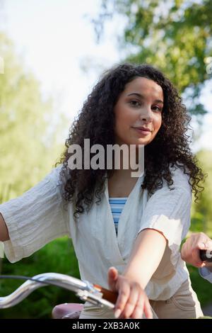 Smiling curly haired woman with bicycle Stock Photo