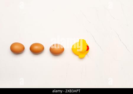 Three eggs and a rubber duck on a marble kitchen counter in a top view Stock Photo