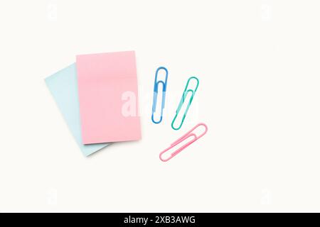 Blank sticky pink and blue paper notes and colored paper clips on a white background with copy space Stock Photo