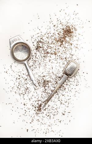 Stainless steel tea infusers and tea strands on a white marble kitchen counter in a top view Stock Photo