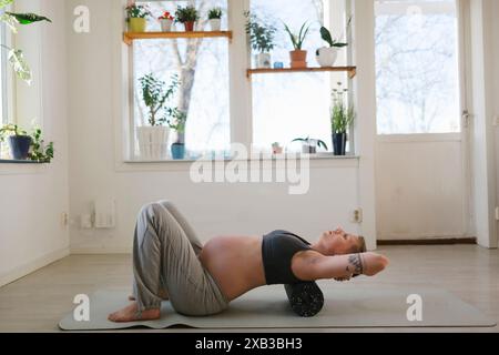 Side view of pregnant young woman practicing yoga at home Stock Photo
