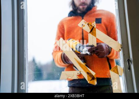 Midsection of man using drill on window glass from outside Stock Photo