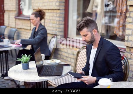 Businessman with diary sitting on chair at sidewalk cafe Stock Photo