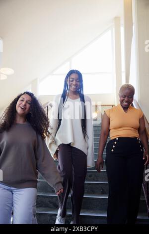 Low angle view of happy young female friends moving down on staircase Stock Photo
