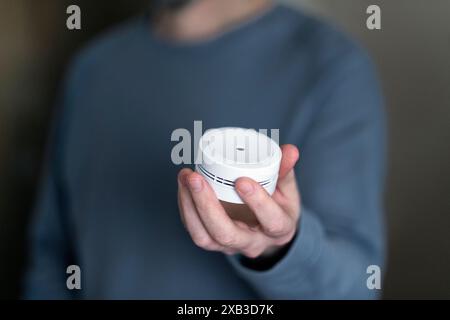 Midsection of man holding smoke detector at home Stock Photo