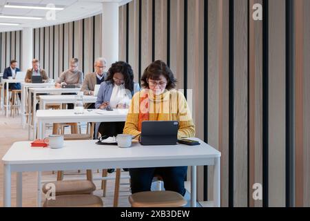Senior businesswoman using tablet PC at table in office cafeteria Stock Photo