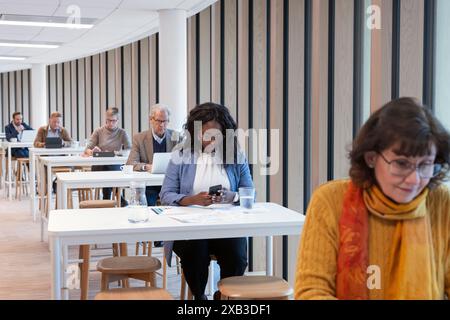 Businesswoman using mobile phone while colleagues sitting at table in office Stock Photo