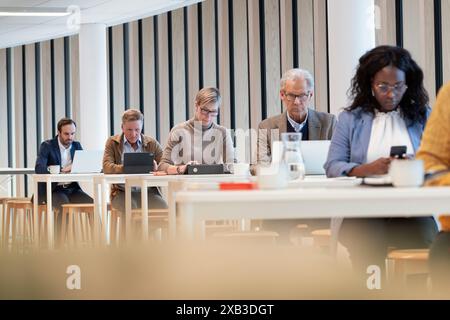 Multiracial colleagues using technologies in office cafeteria Stock Photo