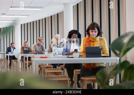 Multiracial colleagues using technologies at table in office cafeteria Stock Photo