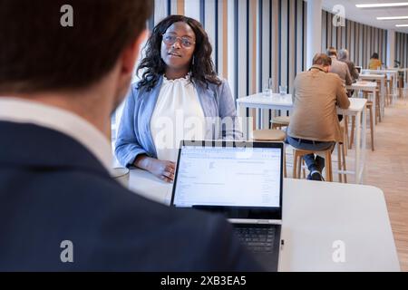 Businesswoman discussing with businessman at table in office cafeteria Stock Photo