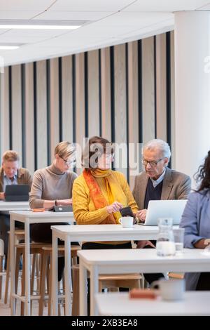 Senior businessman discussing with businesswoman at table in cafeteria Stock Photo