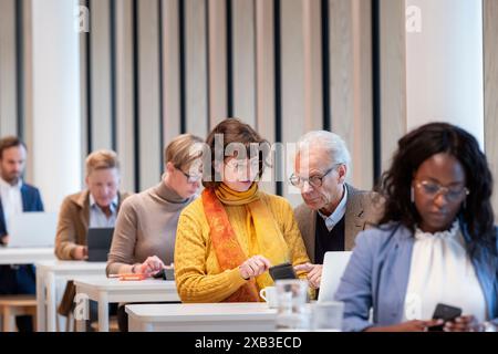 Senior business colleagues discussing over mobile phone at table in cafeteria Stock Photo