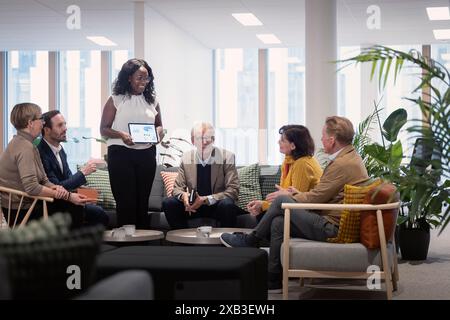 Smiling businesswoman explaining strategy over tablet PC in meeting at corporate office Stock Photo
