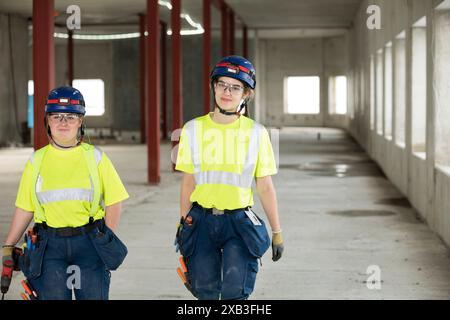 Confident female engineers discussing while walking at construction site Stock Photo