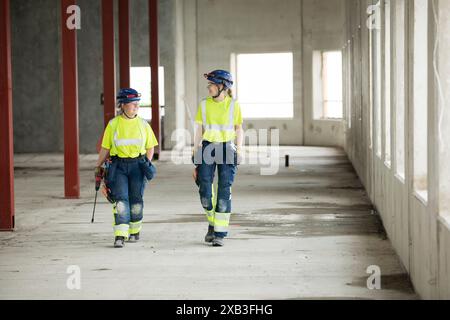 Female engineers discussing while walking at construction site Stock Photo
