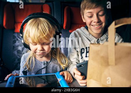 Smiling boy sitting by sister using digital tablet in train Stock Photo