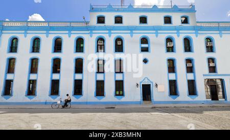 375 Local cyclist at wait stopped on Calle Maceo Street next to the restored northwest facade of the local Post and Telegraph Office. Bayamo-Cuba. Stock Photo